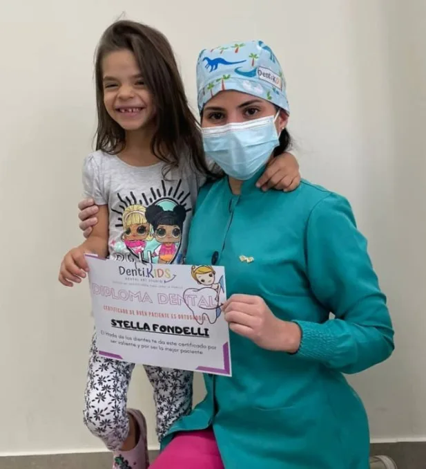 Niña recibiendo su diploma dental tras su cita en OMI Dental